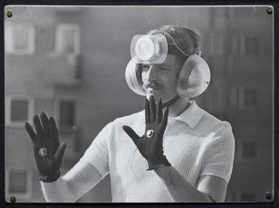 Na czarno-białej fotografii widoczny artysta Krzysztof Wodiczko, który włożył słuchawki na uszy, założył rękawiczki a do czoła przypiął mikrofon. Mikrofon odbierał dźwięki z otoczenia. Za pomocą rękawiczek z czujnikami Wodiczko dopuszczał lub blokował dźw