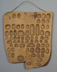Tablica drewniana z wyrytymi wzorami przypominającymi pismo klinowe.