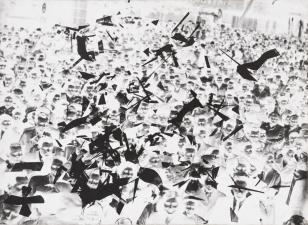 Fotografia czarno-biała naklejona na brązowej tekturze przedstawiająca tłum ludzi zgromadzony na placu w negatywie, na całym obrazie widoczne liczne kawałki ciętego negatywu.