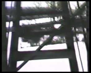Kadr z czarno-białego filmu, przedstawiający zgeometryzowane ciemne formy na jasnym tle.
