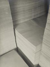Fotografia czarno-biała przedstawiająca ryzy papieru w ujęciu z góry i w dużym zbliżeniu.
