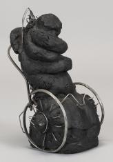 Rzeźba wykonana jest z żeliwa, czarnego, uformowanego w zbitą, nieregularną formę. Po dodaniu do niej metalowych kółek z oparciem, co przypomina wózek inwalidzki forma przybrała ludzkie kształty – przygarbionej postaci siedzącej na wózku.