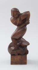 Drewniana rzeźba przedstawiająca zgeometryzowaną postać oracza, jego nogi skierowane są w lewo, a tułów, głowa i uniesiony, zgięty łokieć ręki trzymającej narzędzie rolnicze w prawo. Ma równo przystrzyżone do wysokości podbródka włosy i wąsy.