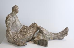 Zgeometryzowana gipsowa rzeźba w kolorze beżowym. Uproszczona forma siedzącej kobiety. Postać w sukni, podparta prawą ręką. Nogi duże, prawa wyciągnięta, lewa podłożona pod nią. Głowa mała z uproszczonymi rysami, dominującym nosem. Gładkie płaszczyzny for