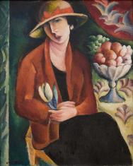 Na ciemnozielonym tle portret kobiety w kapeluszu, z lekko pochyloną w lewo głową, ubraną w czarną sukienkę i brązowy żakiet, w rękach trzyma żółty kwiat na niebieskiej łodydze, obok niej z prawej strony stół, na nim patera z owocami, wokół inne elementy 