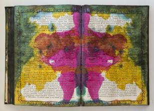 Książka artystyczna wykonana poprzez zamalowanie stron drukowanej książki. Na le druku farby różowa, żółta i zielona rozlane w kształty jak z testu Rorschacha.