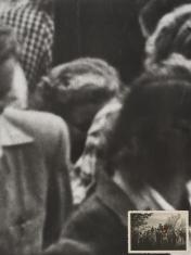 Czarno-biała fotografia w pionie. Przedstawia przybliżony fragment większego obrazu. Widoczna jest grupa ludzi zgromadzonych blisko siebie. Ukazane są głównie głowy i górne partie sylwetek. Ostrość obrazu jest ograniczona, szczegóły twarzy są niewyraźne. 