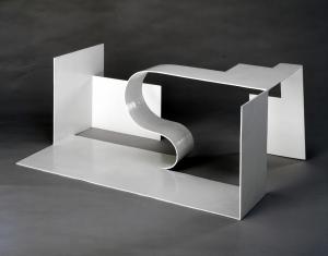 Rzeźba z metalu w kolorze białym i o geometrycznych kształtach - prostopadłościennym formom towarzyszy jedna falista w centrum kompozycji.