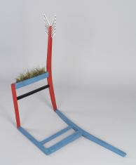 Praca składa się z fragmentu drewnianego krzesła z usunietym siedziskiem (nogi i oparcie pomalowane na czerwono, listwa siedziska na niebiesko, listwa łącząca nogi na czarno). Listwa siedziska została wydrążona i w jej szczelinie artysta zasiał trawę. U g