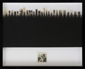 Zdjęcie pracy artysty składające się pociętych w pionowe paski czarnobiałych fotografii ułożonych w rząd w górnej części. Po środku czarny poziomy prostokąt, u dołu mała kwadratowa fotografia.