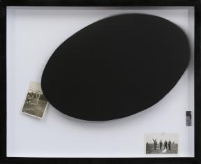 Zdjęcie pracy artysty w czarnej ramie: duży czarny owal w centralnej i prawej części, i dwie małe, stare, czarnobiałe fotografie.