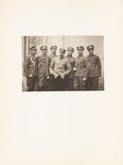 Fotografia portretowa wykonana w kolorystyce sepii, poziomy kadr. Grupa mężczyzn w pełnym umundurowaniu Wojska Polskiego ujęta od linii kolan. Postać w centrum kadru wyróżnia się jaśniejszym kolorem marynarki.