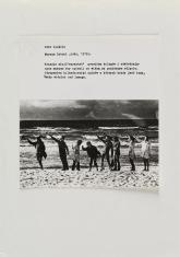 Na zdjęciu praca składająca się z poziomej kartki z opisem, i ułożonego pod nią czarnobiałego zdjęcia, przedstawiającego 8 osób na plaży na tle morza wznoszących prawe ręce do góry.  