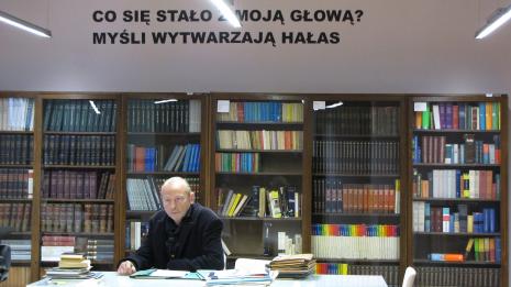 Zbigniew Libera w czytelni biblioteki ms. W głębi praca Pawła Kołwzana Co się stało z moją głową