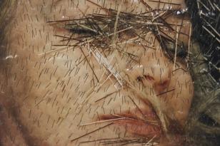 Fotografia twarzy kobiety z gęsto powbijanymi w powierzchnię szpilkami, układającymi się w rytmy i wiry.