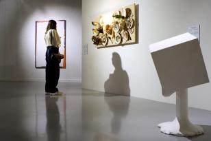Wnętrze sali wystawowej, na pierwszym planie biała rzeźba, na drugim osoba oglądająca obraz na ścianie. 